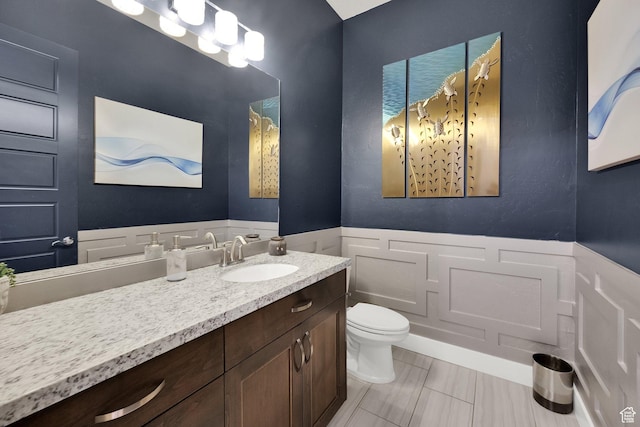 8165 S Willow Creek Cv E, Cottonwood Heights, UT 84093 - bathroom with wainscoting, toilet, a decorative wall, and vanity
