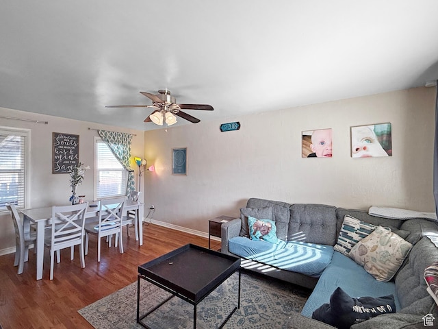 living area with baseboards, ceiling fan, and wood finished floors