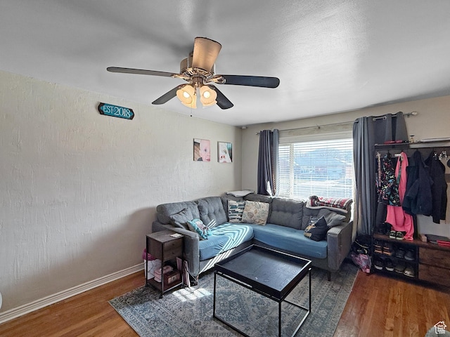 living room featuring baseboards, wood finished floors, ceiling fan, and a textured wall