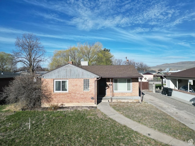 bungalow-style home with a chimney, a front yard, fence, and brick siding