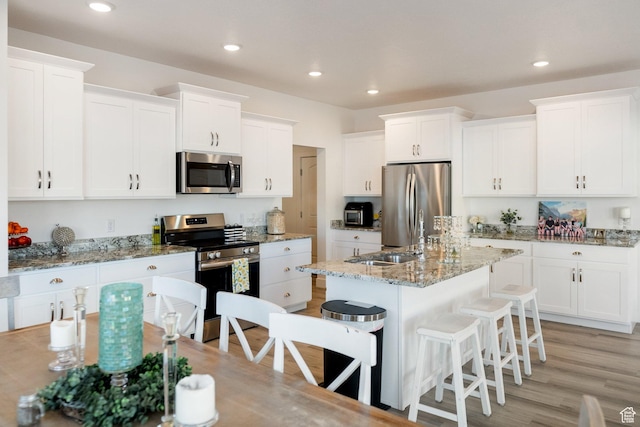 585 W 20 N, Hyrum, UT 84319 - kitchen featuring a sink, white cabinets, a kitchen breakfast bar, and appliances with stainless steel finishes