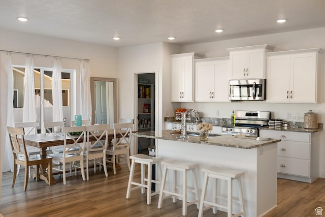 585 W 20 N, Hyrum, UT 84319 - kitchen with a sink, stone countertops, wood finished floors, appliances with stainless steel finishes, and a center island with sink