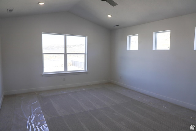 empty room featuring carpet flooring, lofted ceiling, ceiling fan, and a wealth of natural light