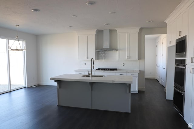 kitchen with wall chimney range hood, dark wood-style flooring, a sink, and tasteful backsplash