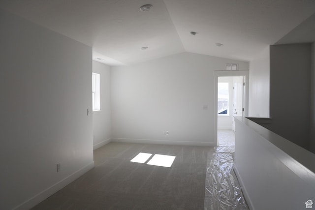 empty room featuring plenty of natural light, light carpet, baseboards, and lofted ceiling