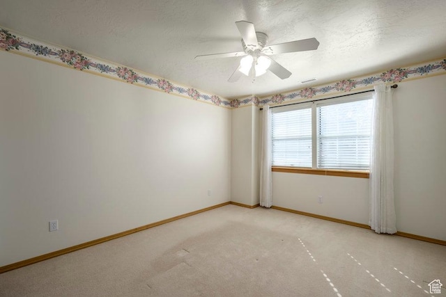 empty room with baseboards, ceiling fan, a textured ceiling, and light colored carpet