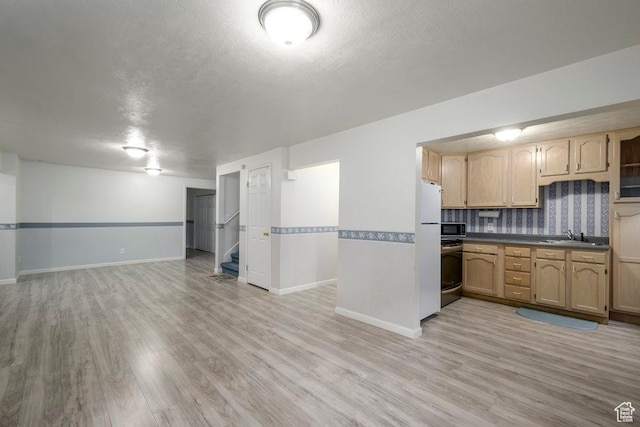kitchen with open floor plan, light wood-style flooring, dark countertops, baseboards, and a textured ceiling