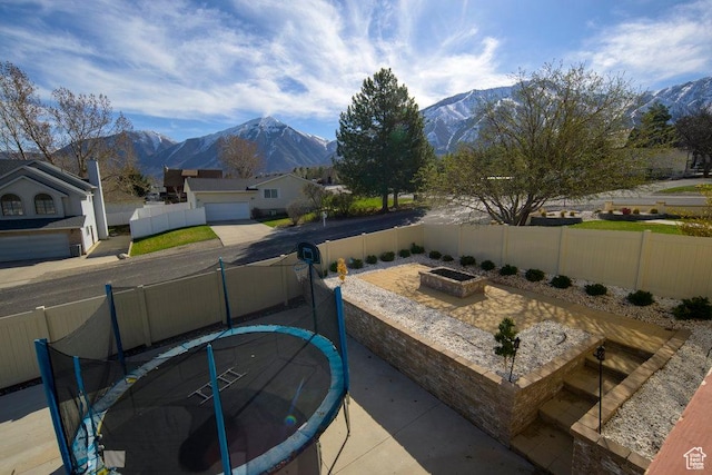 view of patio with a trampoline, a mountain view, and a fenced backyard