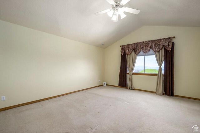 spare room featuring vaulted ceiling, baseboards, a ceiling fan, and light carpet