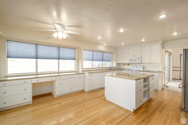 kitchen featuring white appliances, white cabinetry, ceiling fan, light wood-type flooring, and light countertops