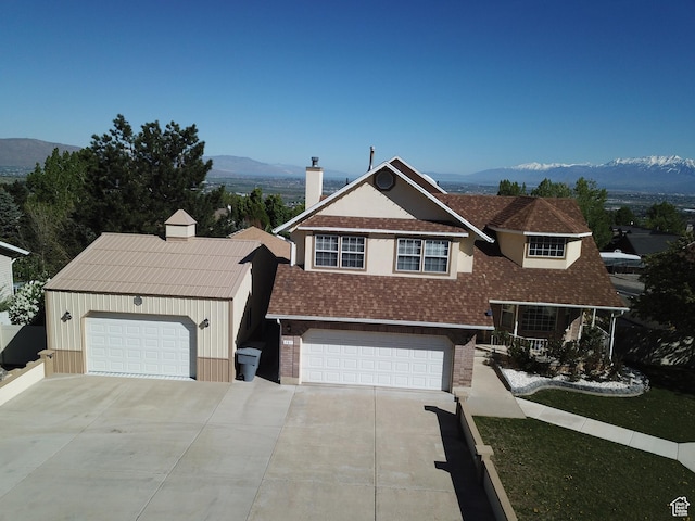 view of front facade with a mountain view, a shingled roof, a chimney, brick siding, and driveway