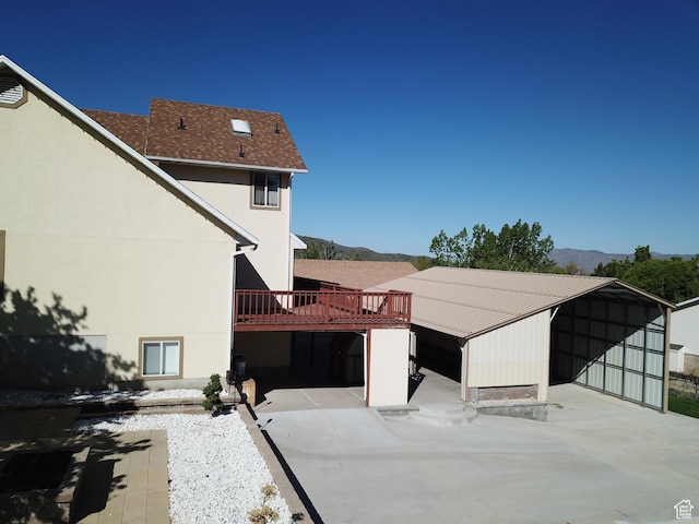 rear view of house with a mountain view, stucco siding, and a carport
