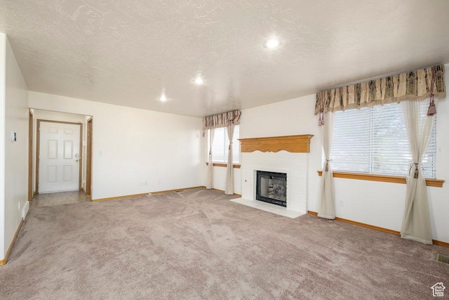unfurnished living room with baseboards, carpet, a fireplace with flush hearth, a textured ceiling, and recessed lighting