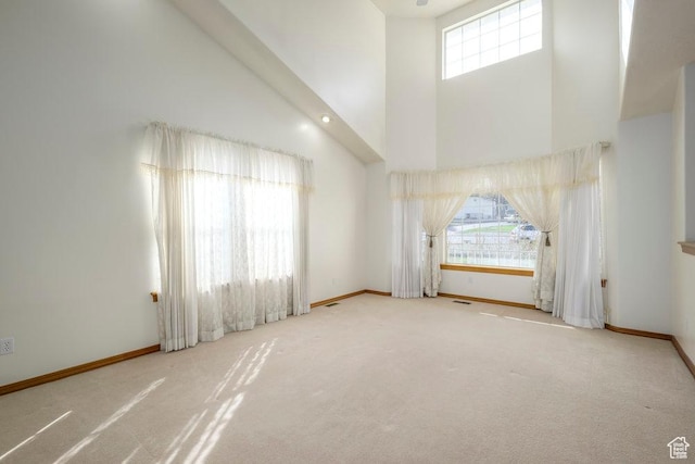 spare room with a towering ceiling, carpet floors, and baseboards