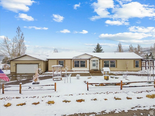 single story home with an outbuilding, concrete driveway, fence, and an attached garage