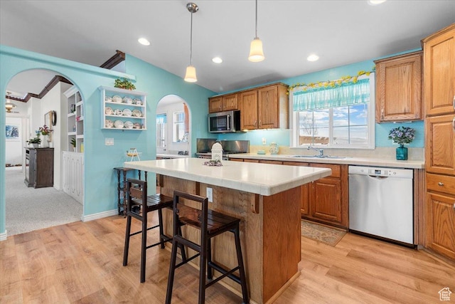 kitchen with light countertops, a sink, a breakfast bar area, stainless steel appliances, and arched walkways