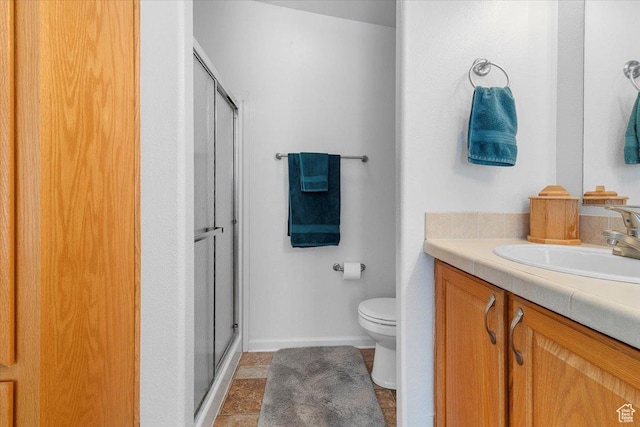 bathroom with toilet, vanity, a stall shower, and baseboards
