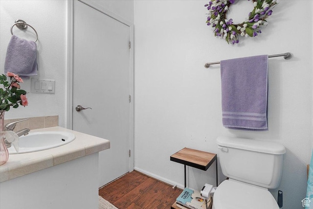 half bathroom featuring wood finished floors, toilet, and vanity