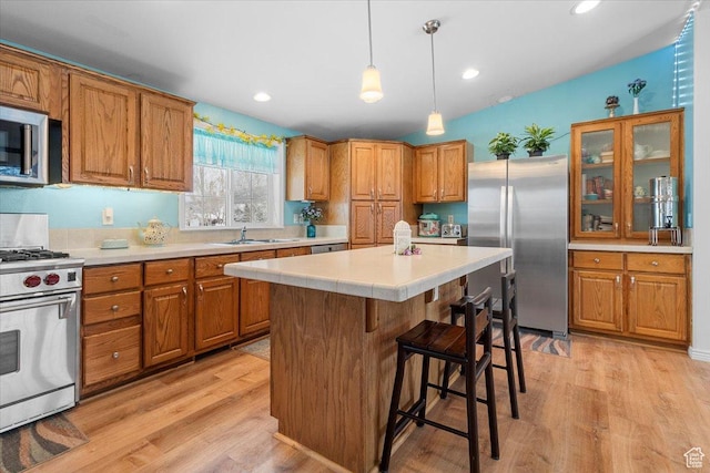 kitchen with brown cabinetry, a kitchen bar, a sink, and stainless steel appliances