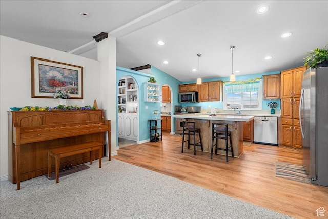 kitchen featuring a kitchen breakfast bar, light countertops, lofted ceiling, a center island, and appliances with stainless steel finishes