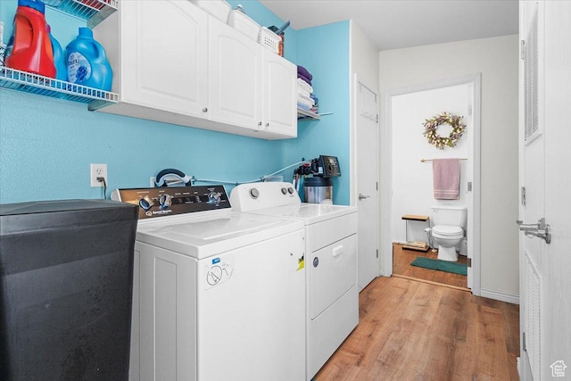 clothes washing area featuring cabinet space, washing machine and dryer, and light wood-type flooring