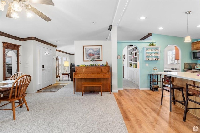 dining room featuring arched walkways, a wealth of natural light, light wood-type flooring, and a ceiling fan