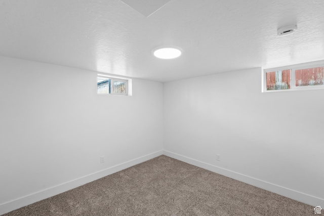 below grade area with baseboards, carpet flooring, and a textured ceiling
