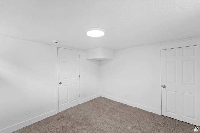 carpeted spare room featuring baseboards and a textured ceiling