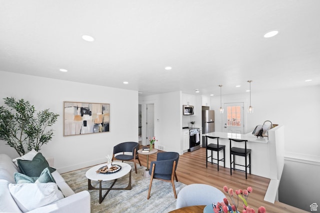 living area featuring baseboards, recessed lighting, and light wood finished floors