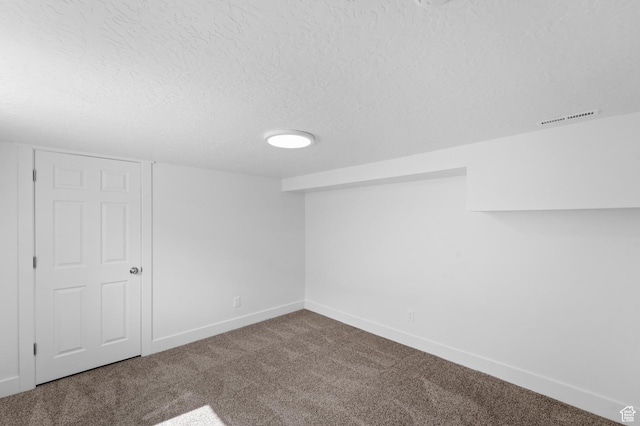 carpeted spare room with a textured ceiling, baseboards, and visible vents