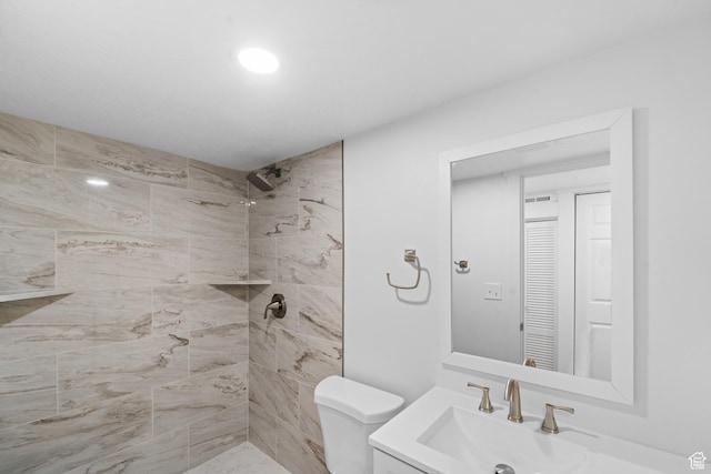 full bathroom with toilet, tiled shower, and vanity