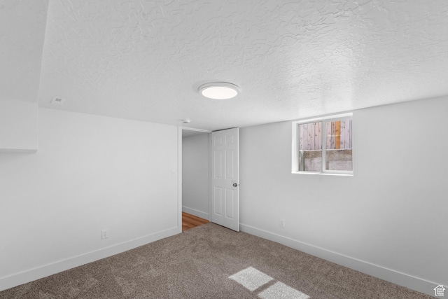 carpeted spare room with baseboards and a textured ceiling