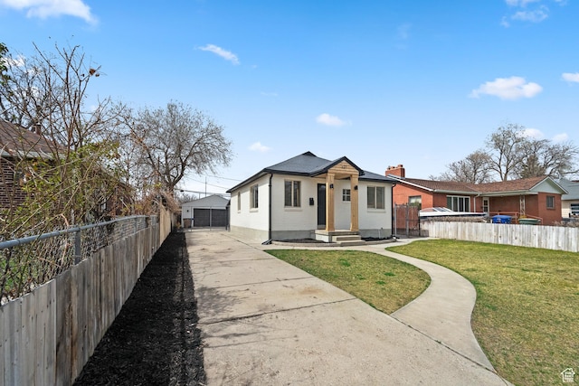 view of front facade featuring a front lawn, an outdoor structure, a detached garage, and fence