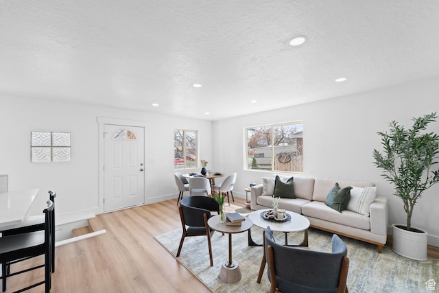 living area featuring baseboards, a textured ceiling, recessed lighting, and light wood-type flooring