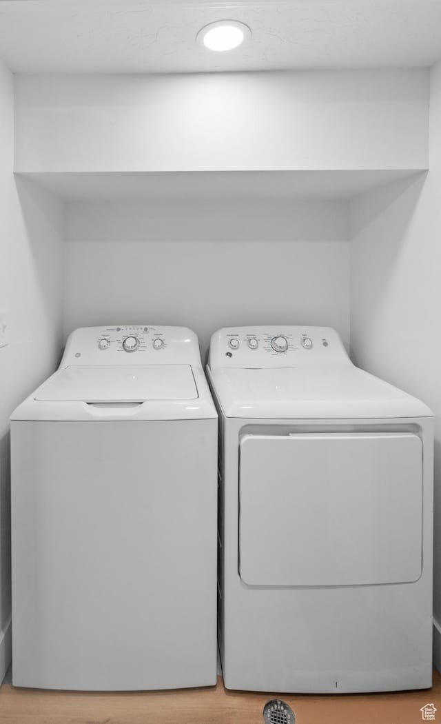 clothes washing area featuring wood finished floors, washing machine and clothes dryer, and laundry area