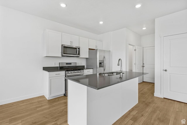 866 S Brubaker Way, Santaquin, UT 84655 - kitchen with stainless steel appliances, dark countertops, light wood-type flooring, a kitchen island with sink, and white cabinets