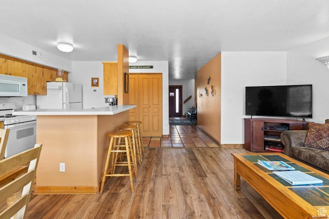 3418 E La Camino, Moab, UT 84532 - kitchen with light countertops, white appliances, a breakfast bar, visible vents, and wood finished floors