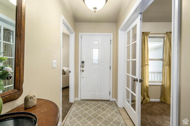 foyer entrance featuring french doors, baseboards, and light carpet