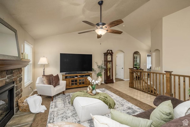 living room with a fireplace, arched walkways, a ceiling fan, tile patterned floors, and baseboards