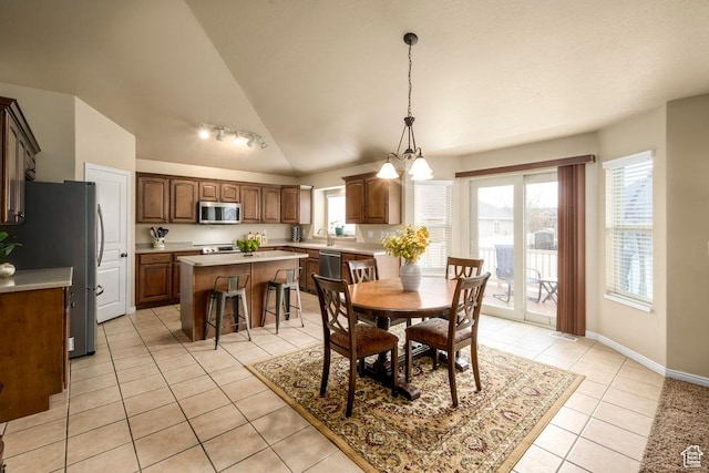 dining area with a notable chandelier, baseboards, vaulted ceiling, and light tile patterned flooring
