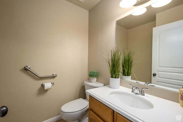 bathroom with toilet, vanity, and visible vents