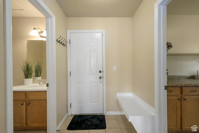 interior space featuring light tile patterned floors, baseboards, and a sink