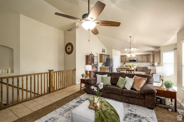living room with high vaulted ceiling, ceiling fan with notable chandelier, and light tile patterned flooring