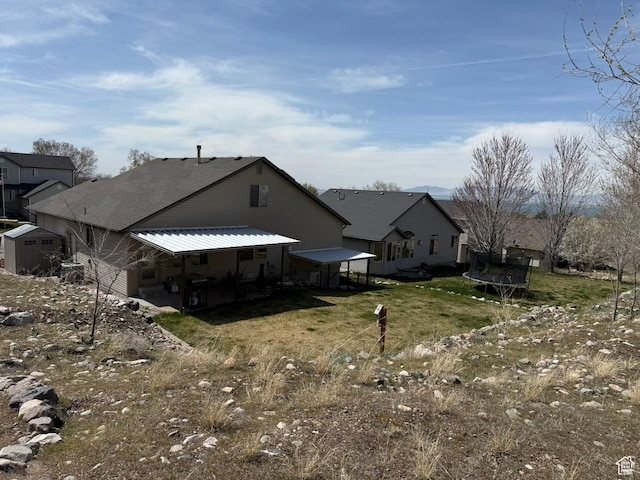245 E 660 S, Willard, UT 84340 - back of house featuring a trampoline, a storage shed, a lawn, an outbuilding, and a patio