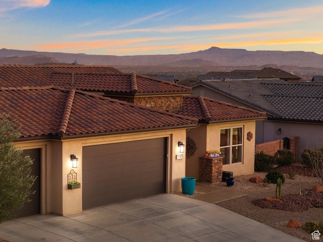 714 N Millcreek Springs Dr, Washington, UT 84780 - view of front of home with a mountain view, stucco siding, a tiled roof, a garage, and concrete driveway