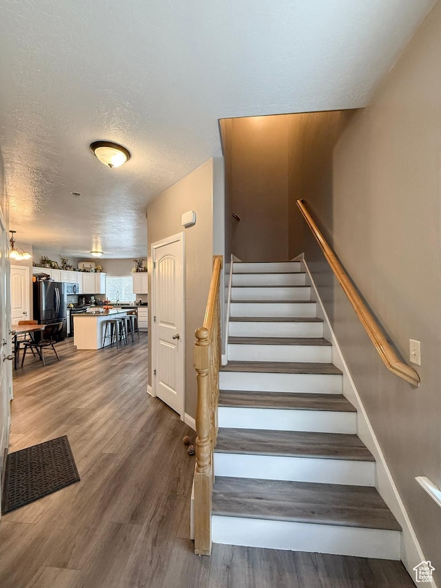 2016 E Cedar Trails Way, Eagle Mountain, UT 84005 - stairs with a textured ceiling, wood finished floors, and baseboards