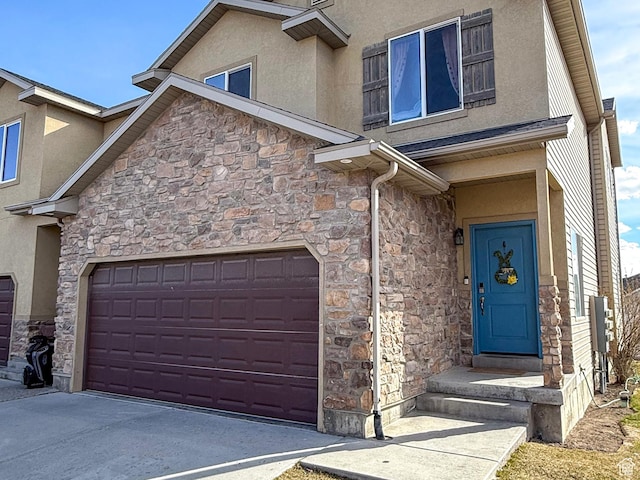 view of exterior entry featuring stone siding, concrete driveway, and stucco siding