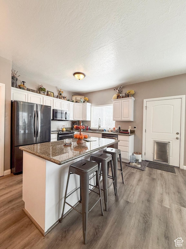 2016 E Cedar Trails Way, Eagle Mountain, UT 84005 - kitchen with stainless steel microwave, freestanding refrigerator, light wood-style floors, a kitchen island, and white cabinets