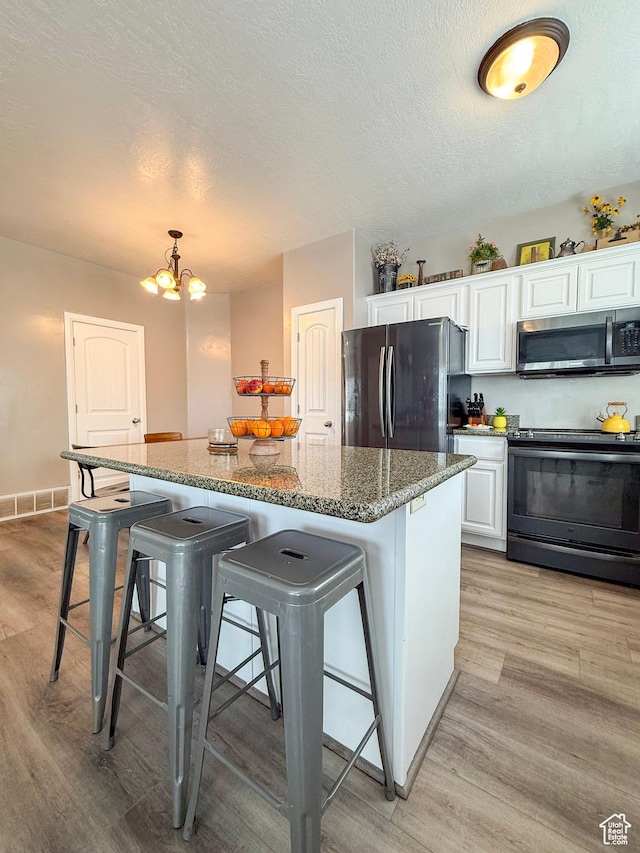 2016 E Cedar Trails Way, Eagle Mountain, UT 84005 - kitchen with black appliances, white cabinets, light wood-style flooring, a kitchen island, and a textured ceiling