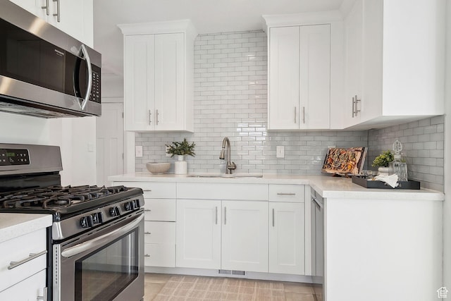 1138 E Hudson Ave, Salt Lake City, UT 84106 - kitchen with decorative backsplash, light countertops, white cabinets, stainless steel appliances, and a sink